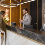Male hotel receptionist assisting female guest