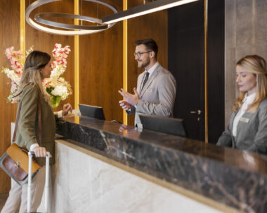 Male hotel receptionist assisting female guest