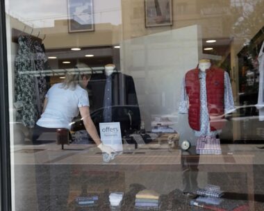 Εργαζόμενη τακτοποιεί βιτρίνα με ρούχα σε κατάστημα