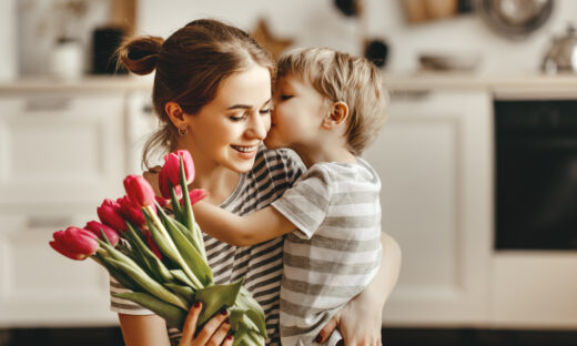 happy mother's day! child son congratulates mother on holiday and gives flowers