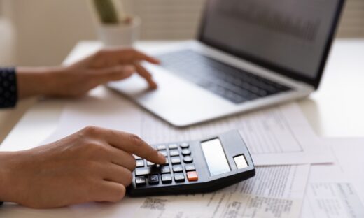 Woman hands at work table with papers accounting sum to pay
