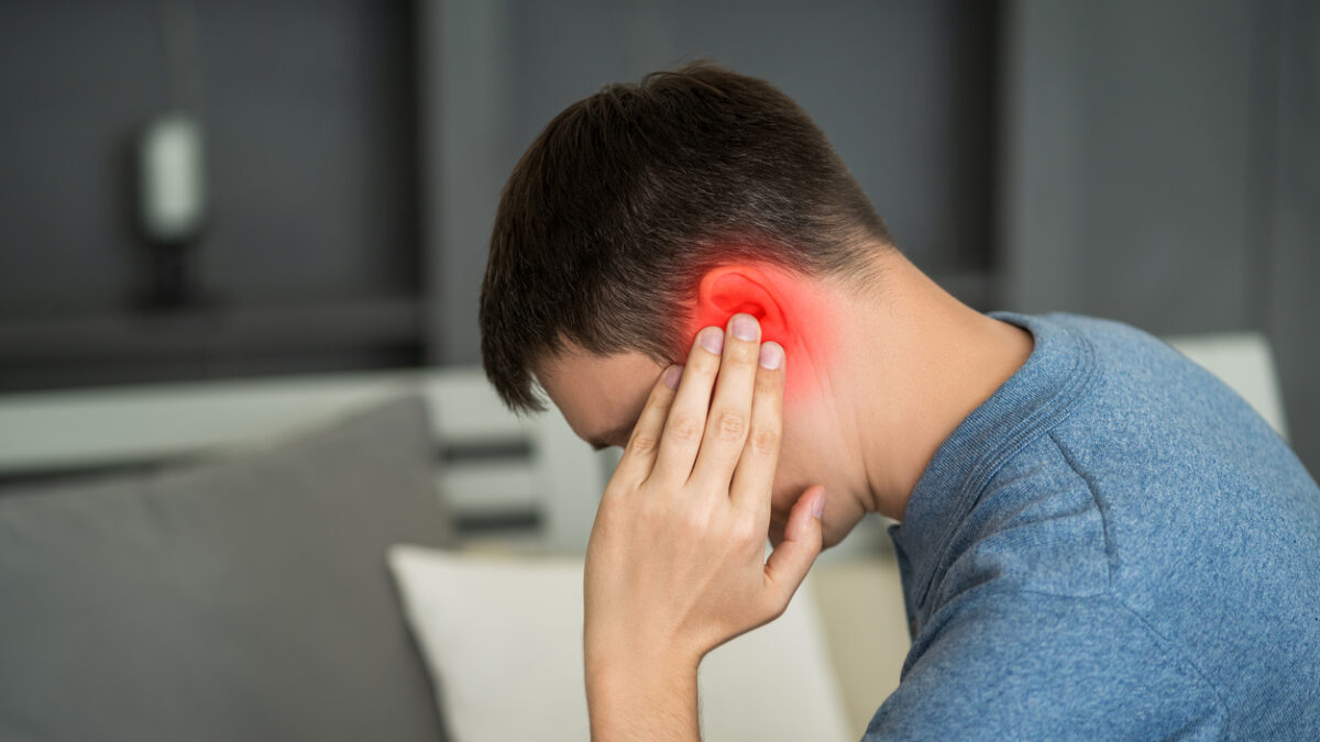 Man with earache, ear pain at home, painful area highlighted in red