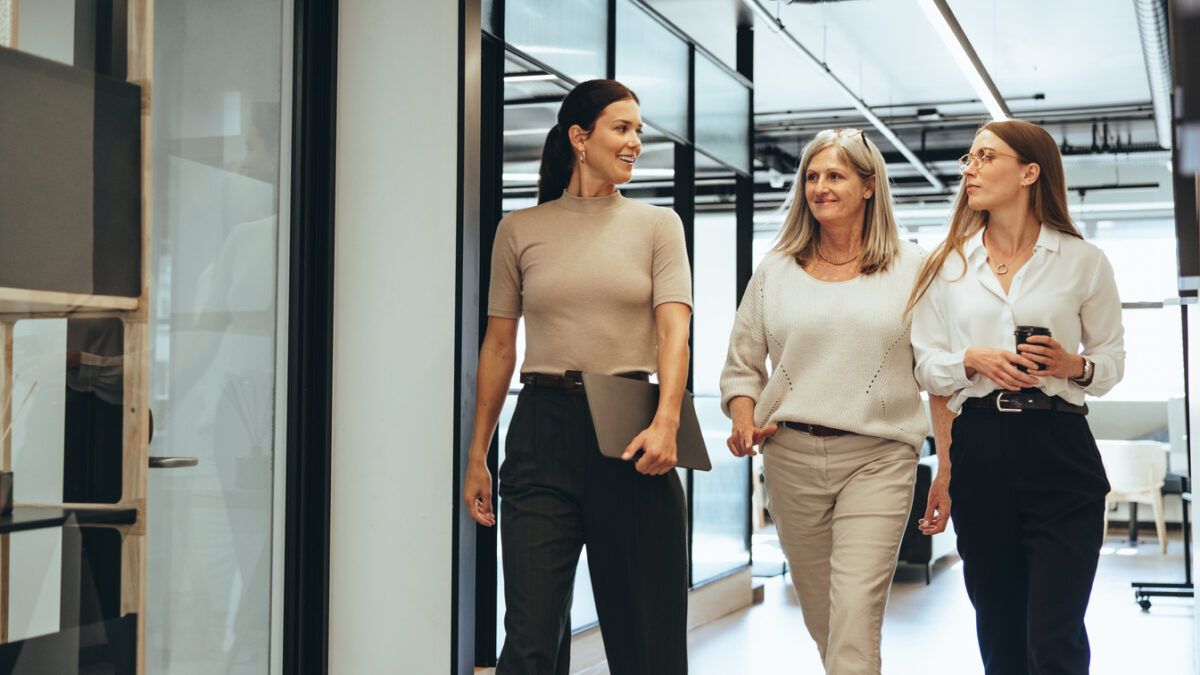 Three cheerful businesswomen walking together in an office