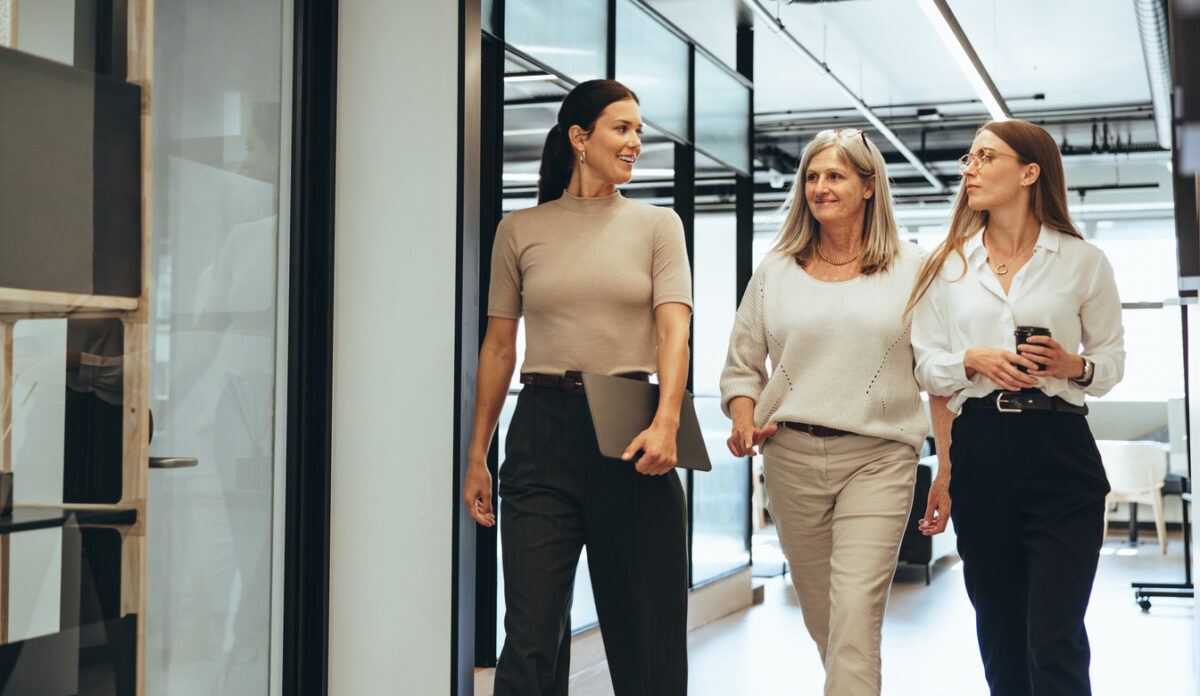 Three cheerful businesswomen walking together in an office
