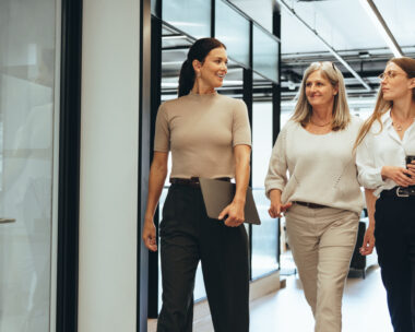 Three cheerful businesswomen walking together in an office