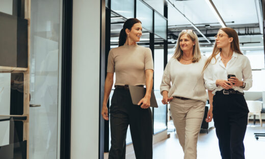 Three cheerful businesswomen walking together in an office