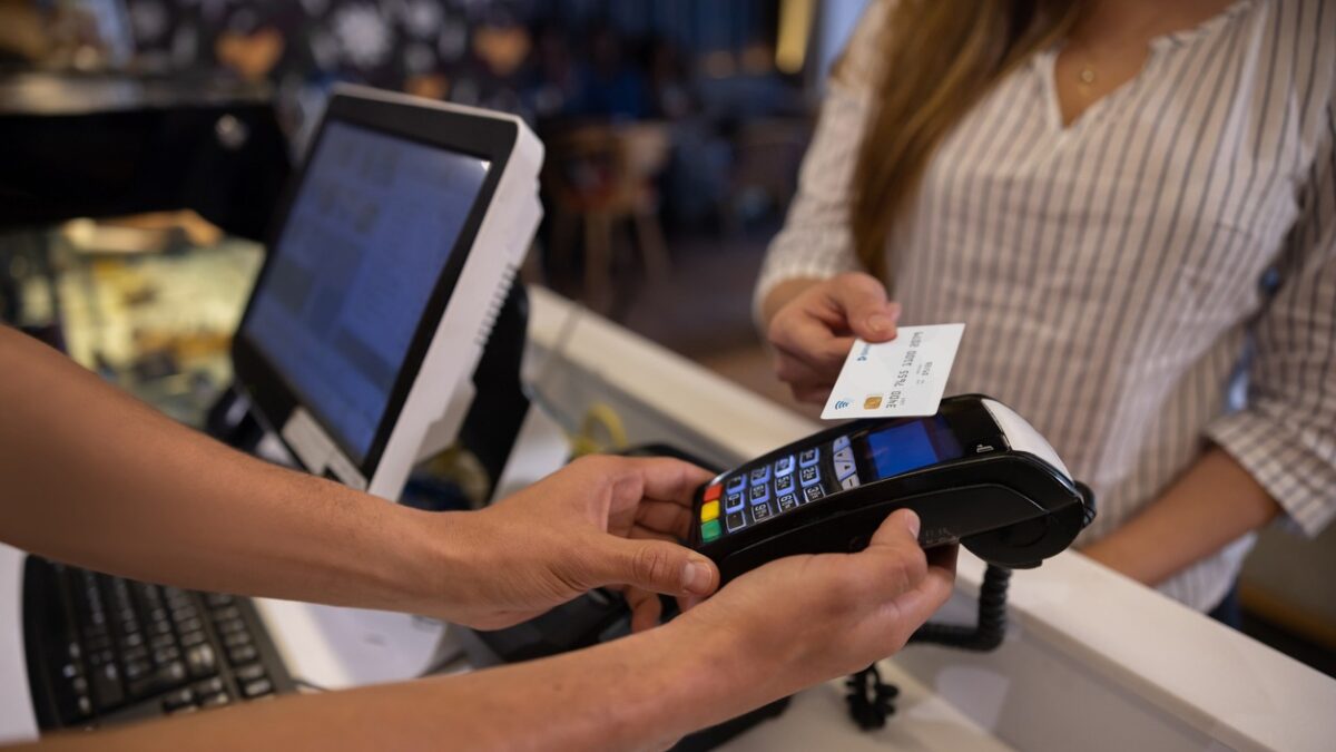 a woman making a contactless payment at a cafe using her credit card