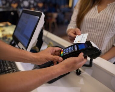 a woman making a contactless payment at a cafe using her credit card