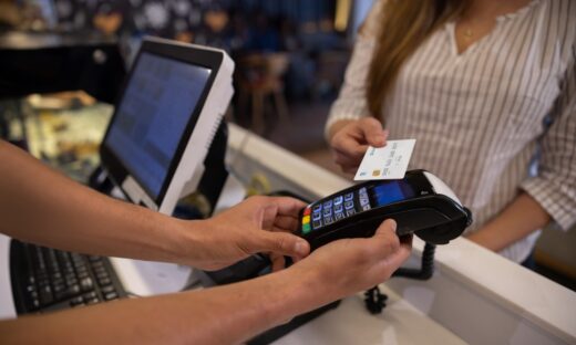 a woman making a contactless payment at a cafe using her credit card