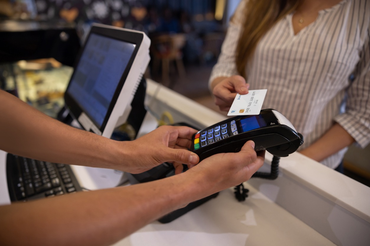 a woman making a contactless payment at a cafe using her credit card