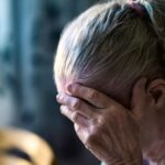 Ηλικιωμένη γυναίκα κρατά το κεφάλι της