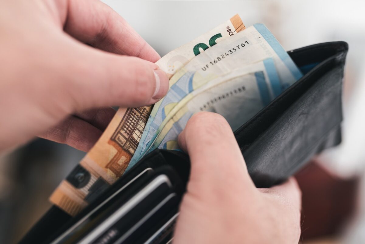 close-up view of hands taking money out of a wallet