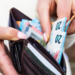 A woman takes Euro banknotes from a leather wallet