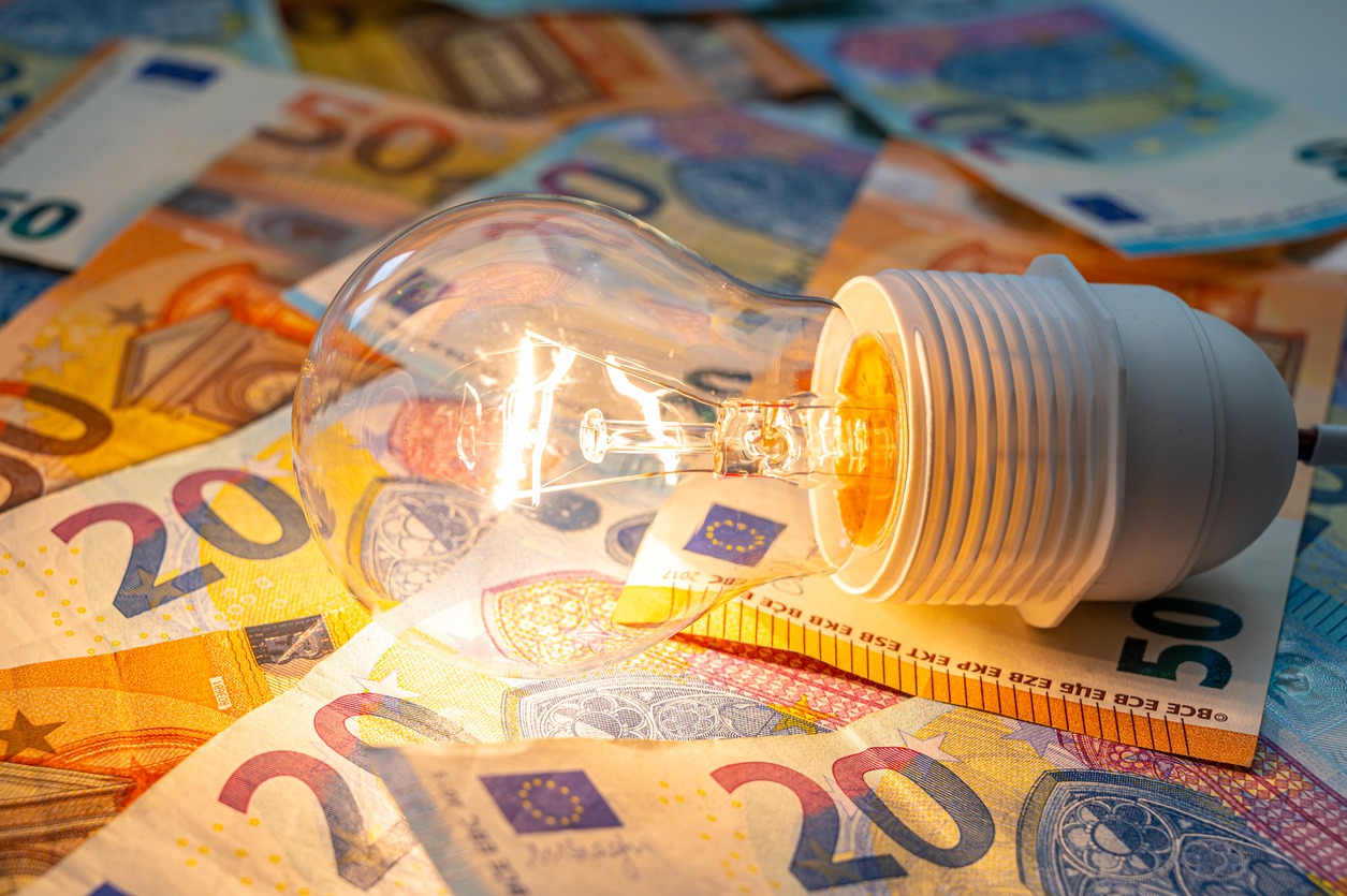Light bulb lit, above euro banknotes