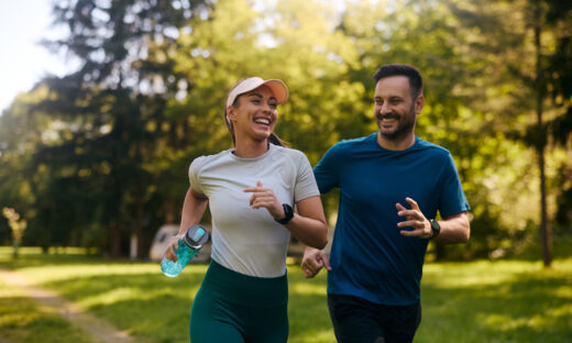 Happy athletic couple having fun while running together in nature. Copy space.
