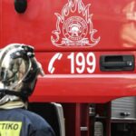 Πυροσβέστης μπροστά από το πυροσβεστικό όχημα