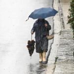 Γυναίκα με ομπρέλα λόγω έντονης βροχόπτωσης στην Αττική