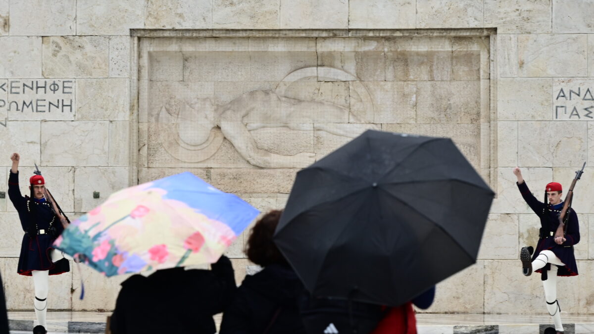 τουρίστες με ομπρέλες μπροστά από το μνημείο του Άγνωστου Στρατιώτη