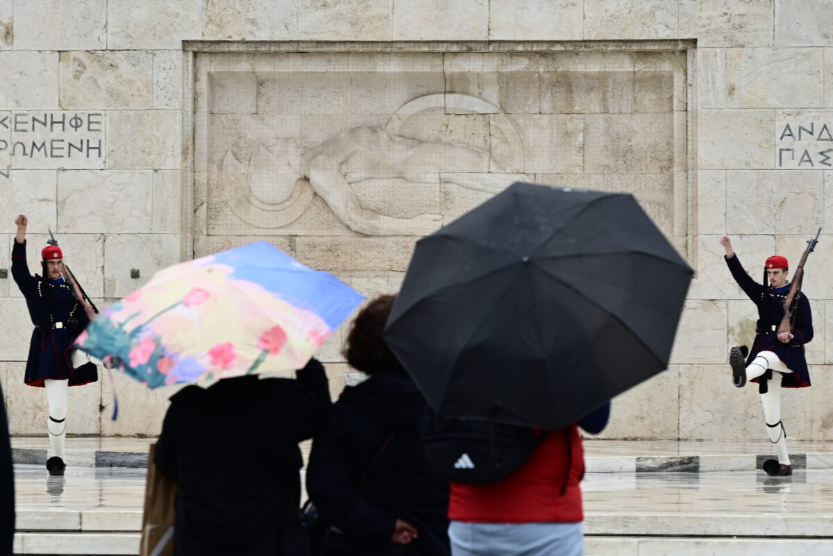 τουρίστες με ομπρέλες μπροστά από το μνημείο του Άγνωστου Στρατιώτη