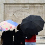 τουρίστες με ομπρέλες μπροστά από το μνημείο του Άγνωστου Στρατιώτη