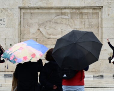 τουρίστες με ομπρέλες μπροστά από το μνημείο του Άγνωστου Στρατιώτη