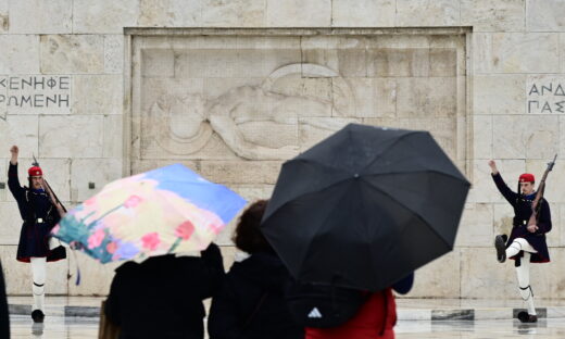 τουρίστες με ομπρέλες μπροστά από το μνημείο του Άγνωστου Στρατιώτη