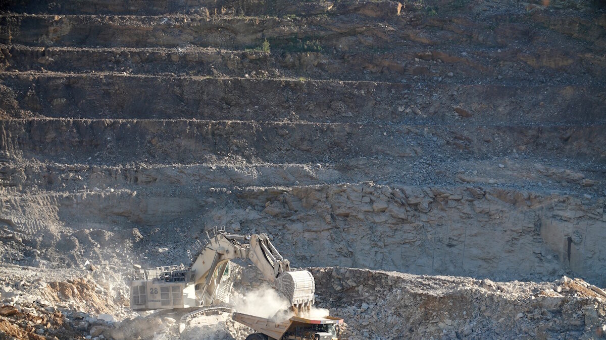 An excavator fills a dumper truck with ore at the Kibali gold mine
