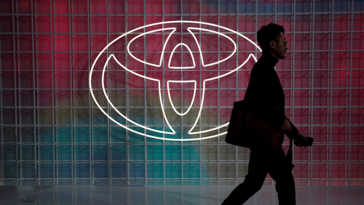 A man walks past a Toyota logo