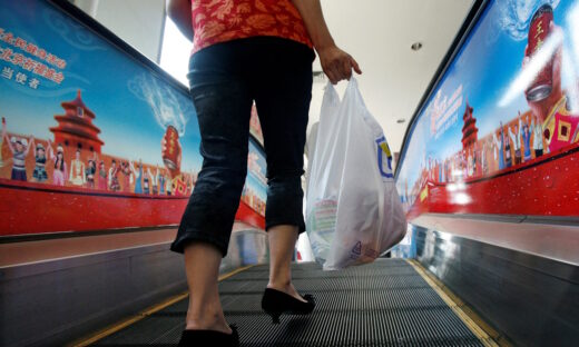 A shopper carries groceries she bought in a plastic bag in Beijing