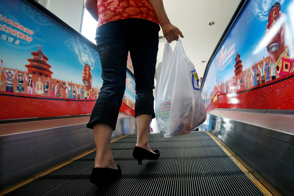 A shopper carries groceries she bought in a plastic bag in Beijing