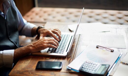 Senior businessman typing on a laptop in a coworking space