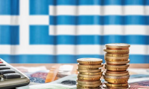 Euro banknotes and coins in front of the national flag of Greece