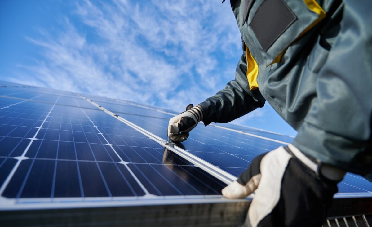 Close up of man technician in work gloves installing stand-alone photovoltaic solar panel system
