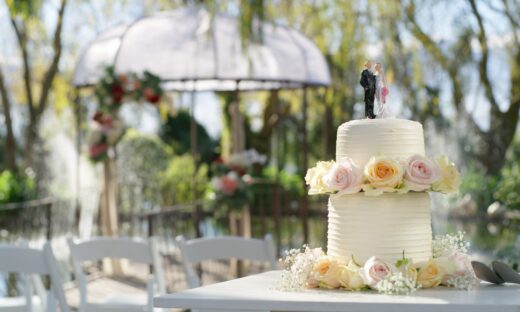 Shot of a cake topped with plastic bride and groom figurines at an outdoor wedding