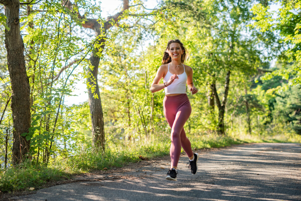 Female athlete having training in park at sunny summer day.