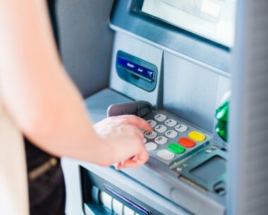 An adult person pressing on ATM machine keypad number to withdraw cash money