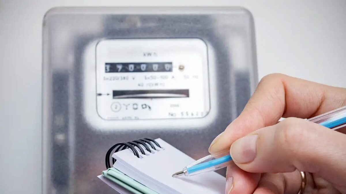 Woman with pen and notepad writes the electricity meter readings. Payment of utility services.