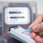 Woman with pen and notepad writes the electricity meter readings. Payment of utility services.