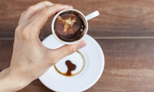 A caucasian woman is performing fortune reading ( kahve fali ) using leftover coffe grounds in ceramic Turkish coffe cup. A popular activity in Turkey. Coffee drops form shapes and patterns.