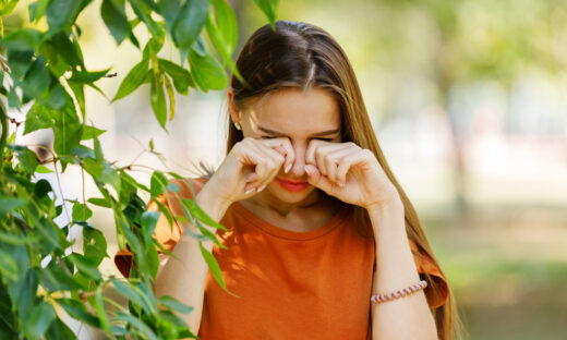 Beautiful Woman with Long Hair is Walking in Public Park and Rubbing her Eyes Due to the Problems with Allergy or Sight.