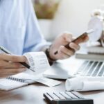 young man holding pen with bills working for calculate business data, taxes, bills payment,