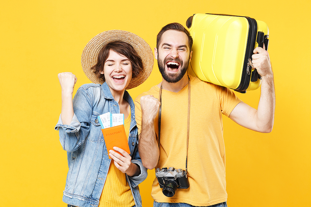 Happy young tourists couple friends guy girl isolated on yellow background. Passenger traveling abroad on weekends. Air flight journey concept. Hold passport tickets suitcase doing winner gesture