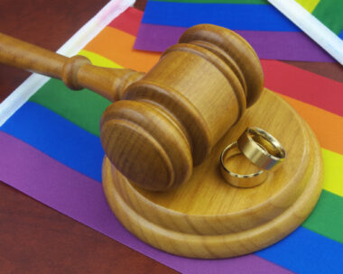 LGBT marriage, equality and laws concept. Wedding rings, wooden gavel and LGBT flags