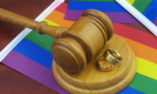 LGBT marriage, equality and laws concept. Wedding rings, wooden gavel and LGBT flags