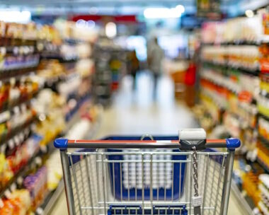 A shopping cart by a store shelf in a supermarket