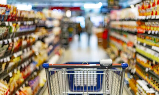 A shopping cart by a store shelf in a supermarket