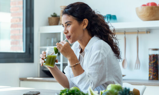 Shot of pretty woman looking to sideways while drinking fruit detox juice in the kitchen at home.