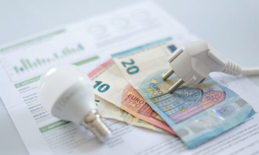 A white electric cap, a light bulb and euro banknotes on an electric bill