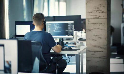 Closeup rear view of a young man coding on multiple computers