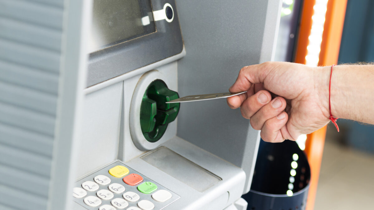 Human hand inserting a credit card into an ATM